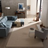 modernes Wohnbeispiel mit maßgefertigtem Teppich, modern gepolsterten Sitzmöbeln sowie leichten Fensterdekorationen